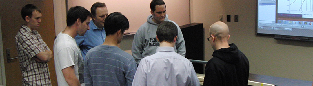 Students gather around a table during a demo. 